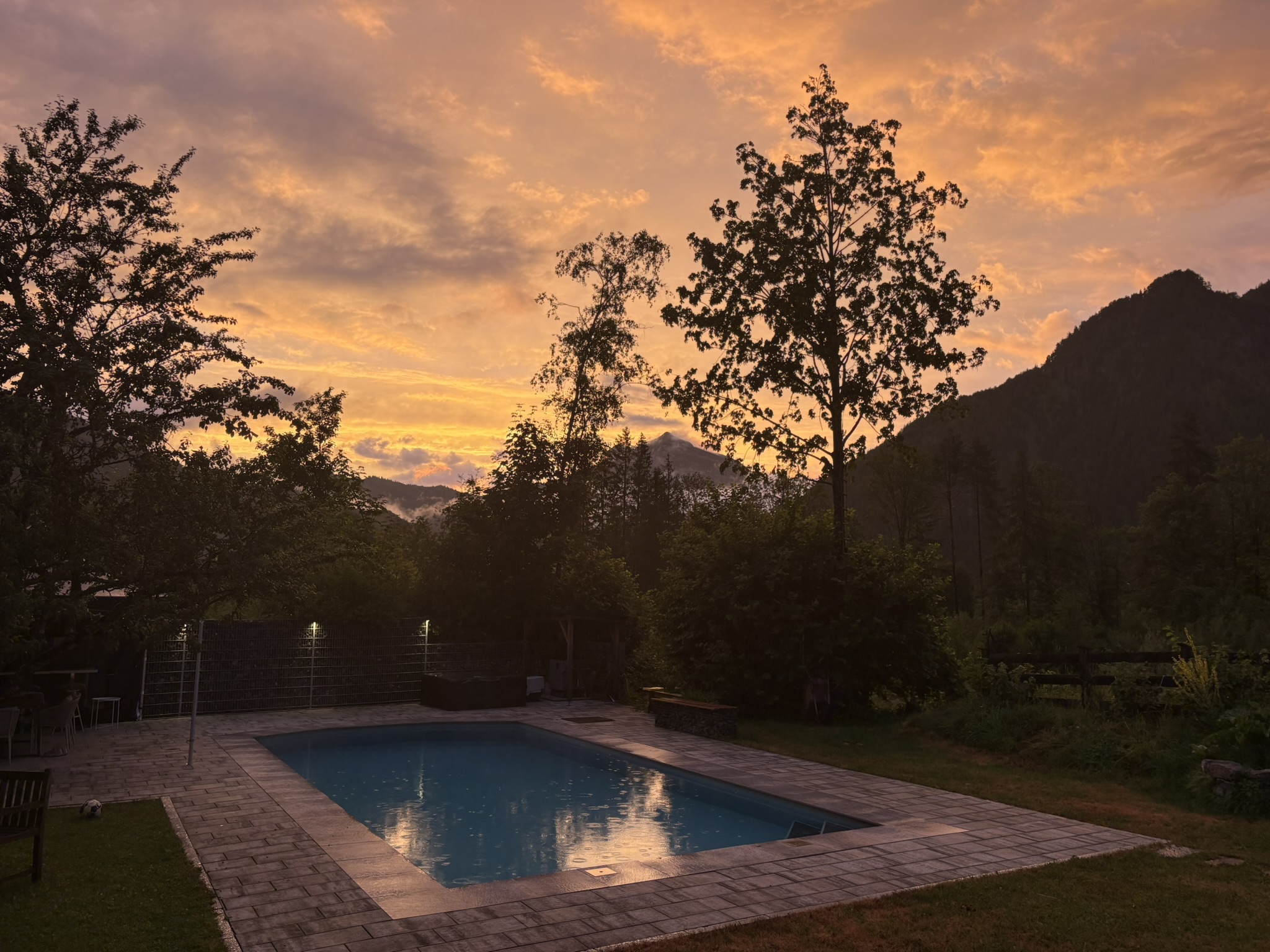 Pool bei Sonnenuntergang mit Tiroler Bergsilhouette
